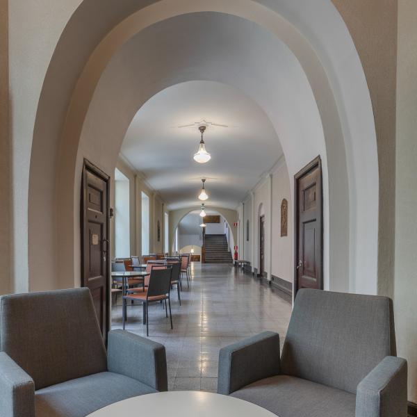 Halliknande korridor med fåtöljer och stolar runt små bord.