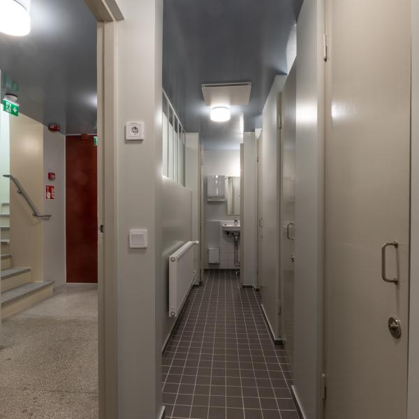 Korridor med klinkergolv med dörrar längs med och ett handfat.